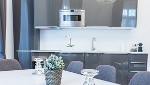 Een moderne keuken met een inbouwoven, een spoelbak en een eethoek met tafel en stoelen.