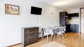 Ein modernes Apartment mit Essbereich, Küchenzeile und einem an der Wand befestigten Flachbildfernseher.