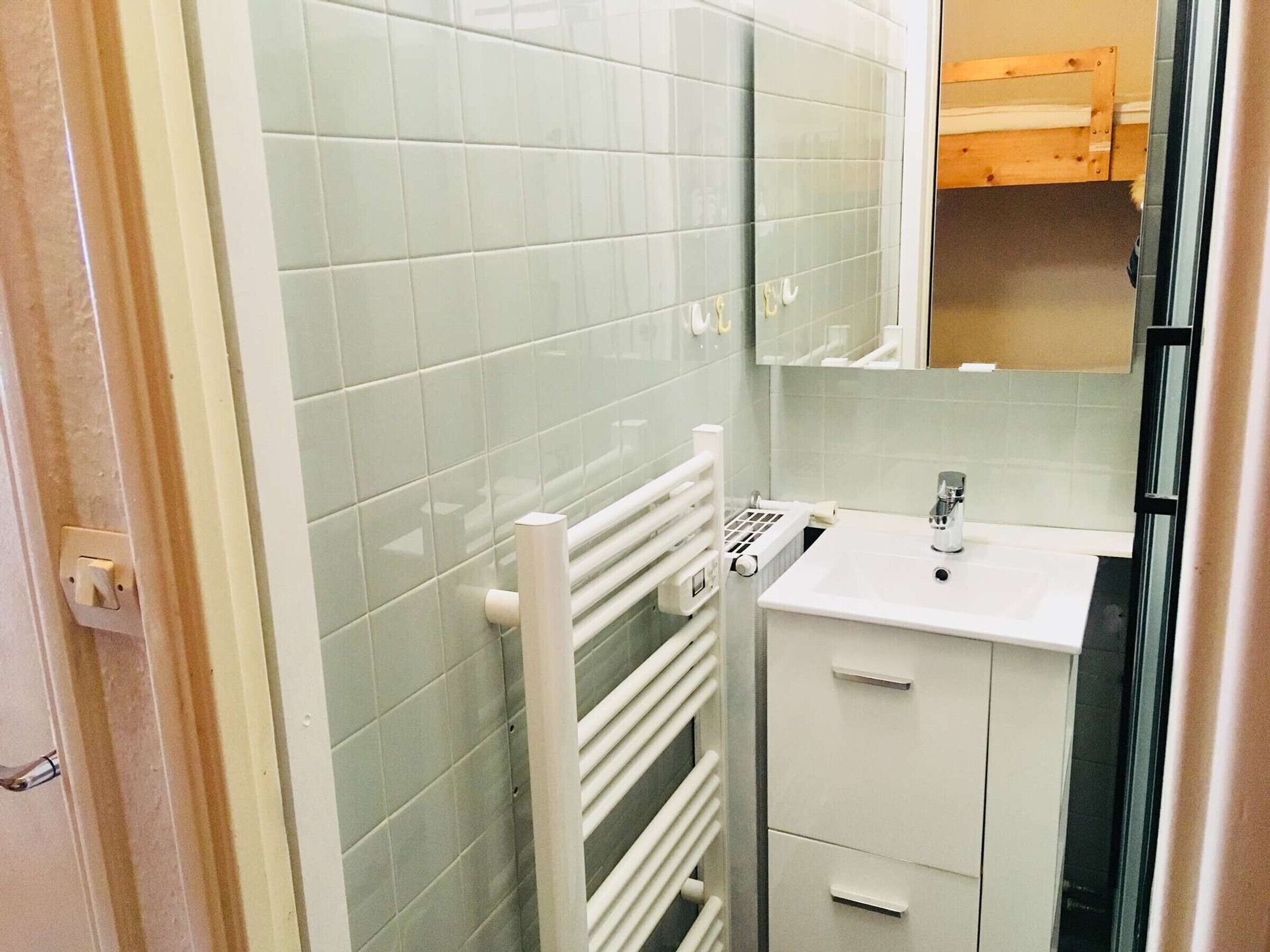 Une salle de bain avec un lavabo blanc, un miroir et un porte-serviettes.