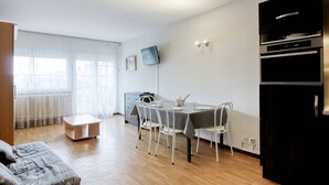 Eine moderne Wohnung mit Essbereich, einer Couch, einem Fernseher und einer Küche.
