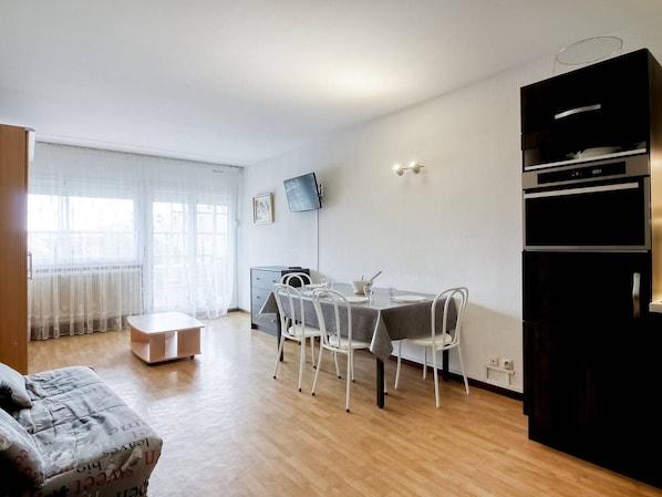 Um apartamento moderno com área de jantar, sofá, televisão e cozinha.