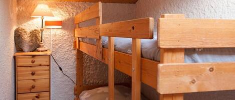 A bunk bed room with a wooden dresser and a lamp.