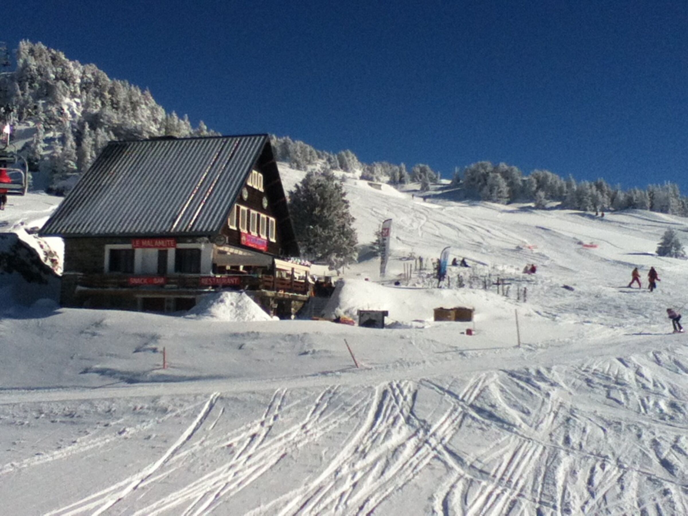 A chalet-style building with a sloped roof, situated on a snowy slope.