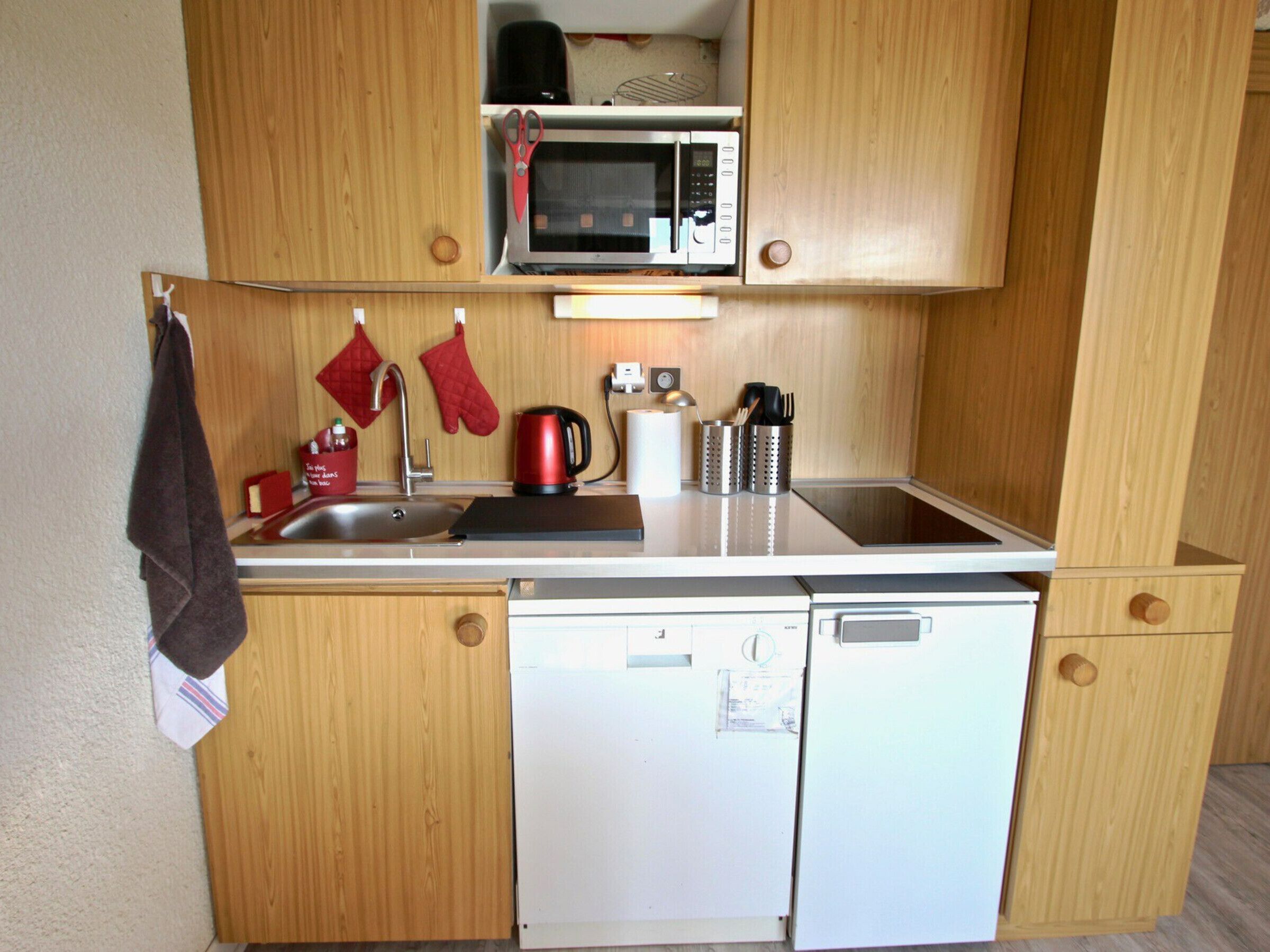 Een compacte kitchenette met een magnetron, spoelbak en een kleine vaatwasser.