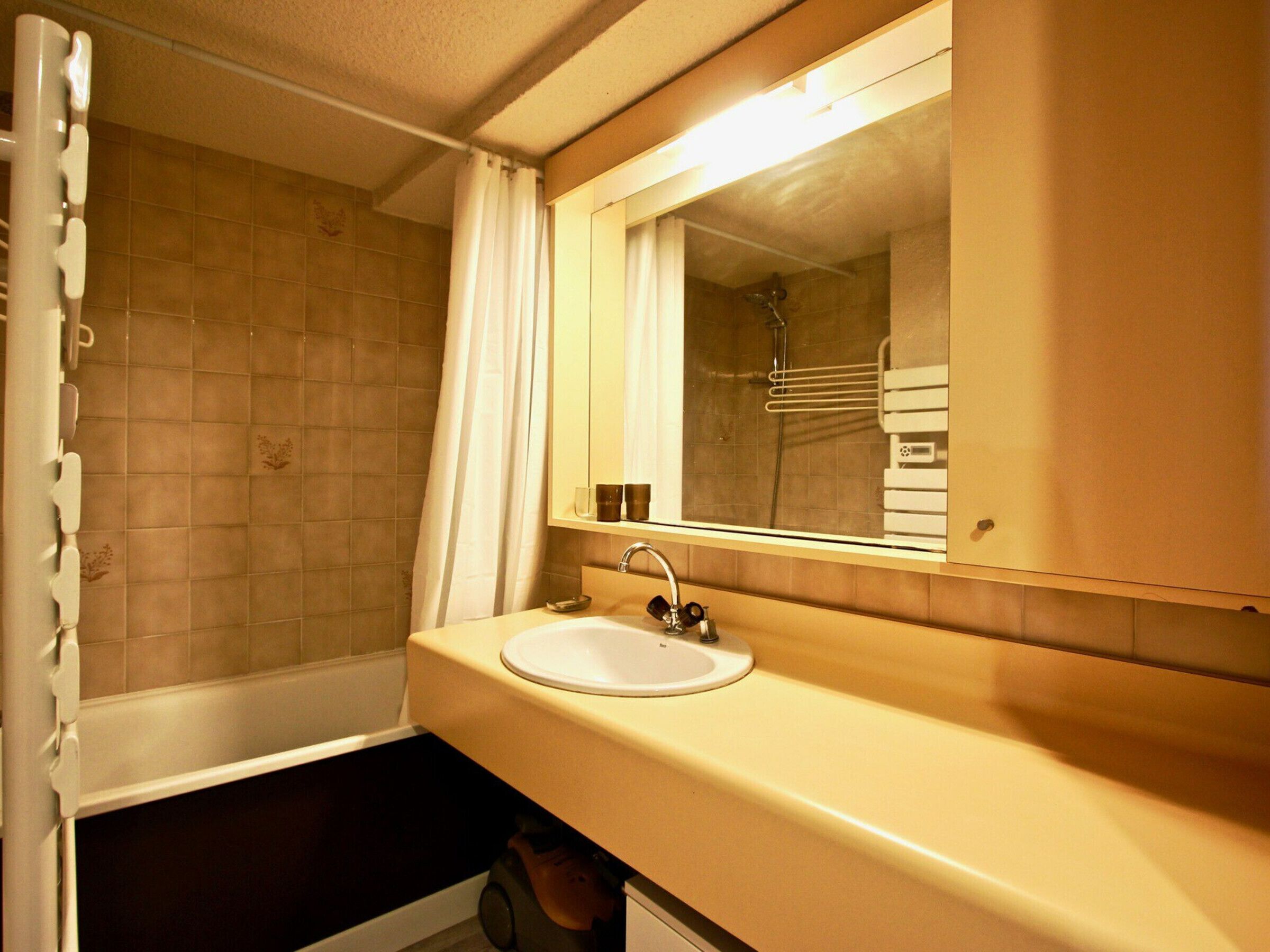 A bathroom with a bathtub, a sink, and a mirror.