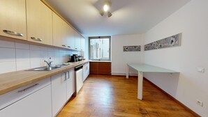 A modern kitchen with white cabinets, a wooden countertop, a dishwasher, and a window with a view of buildings. - haussmann duplex 5br 3bth city center 225m2 (Colmar)