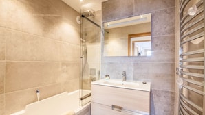 A modern bathroom with a glass shower enclosure, a white bathtub, and a vanity with a mirror. - Joux Plane A202 Beautiful central apartment 8 ppl (MORZINE)