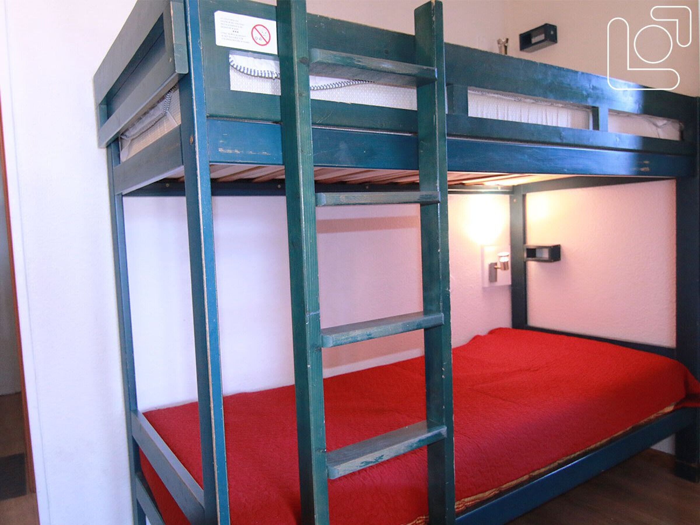 A bunk bed with a red mattress and a ladder.