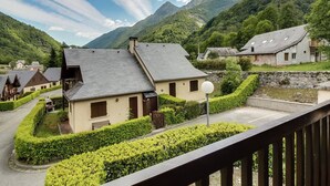 Un village de montagne aux maisons traditionnelles, sous un ciel dégagé, entouré d’une végétation luxuriante.