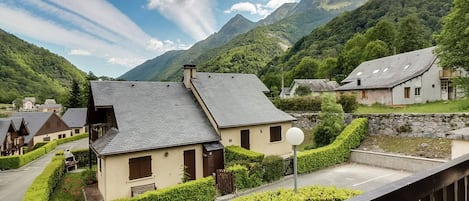 Un pueblo de montaña con casas tradicionales, cielo despejado y abundante vegetación.
