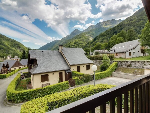 A mountain village with traditional houses, a clear sky, and lush greenery.