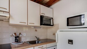 Une cuisine compacte avec des meubles blancs, un four à micro-ondes, un lave-vaisselle et un lave-linge.