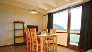 Un coin repas avec une table et des chaises en bois, une petite étagère et un téléviseur.