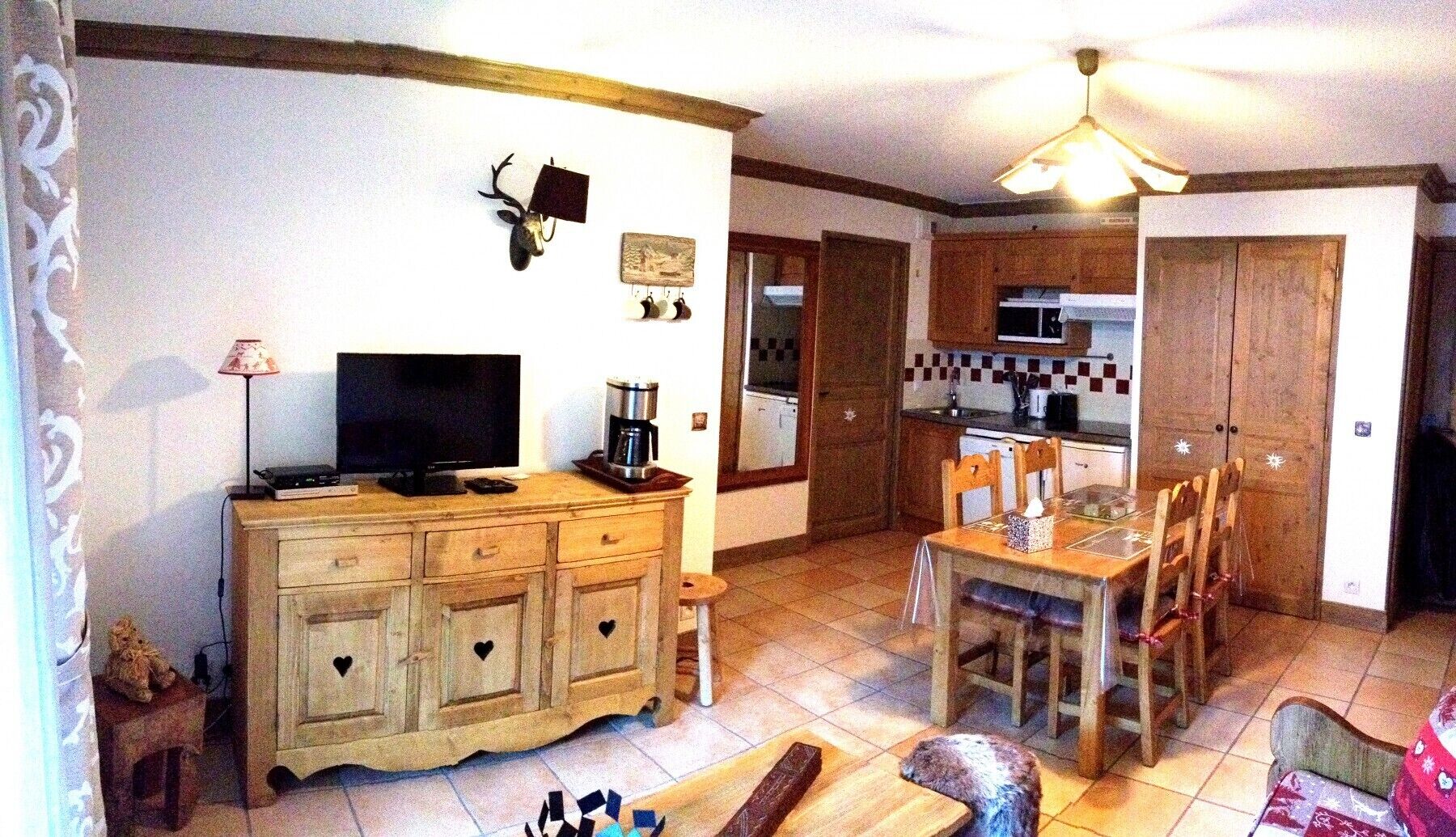 A compact living space with a television, coffee maker, and a dining area with chairs and a table.