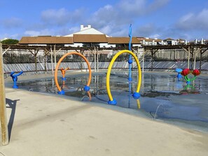 Un espace de jeux aquatiques avec des structures colorées et un bâtiment en arrière-plan.