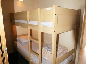 Habitación con literas y una puerta entreabierta.