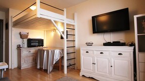 A compact room with a bunk bed, a television, a microwave, a small table, and a cabinet.