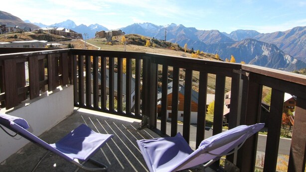 A balcony with two chairs overlooking a mountainous landscape.