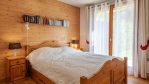 A wooden-paneled bedroom with a bed, bedside tables, a lamp, and a bookshelf. - Jeanette 2 : Nice sunny apartment with terrace (MORZINE)