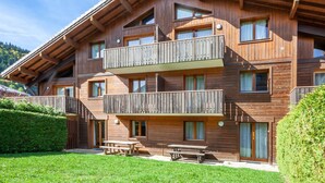 A multi-story wooden chalet with balconies, outdoor seating, and a well-maintained garden. - Jeanette 2 : Nice sunny apartment with terrace (MORZINE)