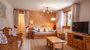 A cozy living room with a wooden sofa, a wooden coffee table, a TV, and a map on the wall. - Jeanette 2 : Nice sunny apartment with terrace (MORZINE)