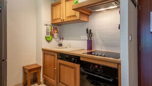 A compact kitchen with wooden cabinets, a dishwasher, an oven, and a small countertop. - Jeanette 2 : Nice sunny apartment with terrace (MORZINE)