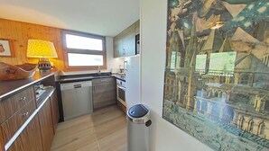 Une cuisine compacte avec des meubles en bois, un évier en acier inoxydable et une cuisinière moderne.