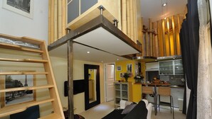 Un espacio habitable compacto con zona de entrepiso, kitchenette y sofá.