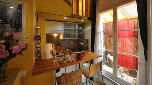 Una cocina compacta con encimera de madera, un lavabo y una ventana con cortinas rojas.