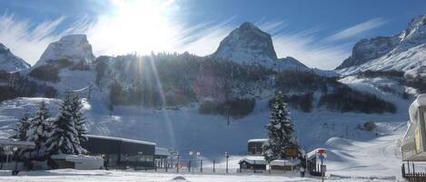 A snow-covered mountain landscape with a clear sky and the sun shining brightly.
