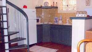 A kitchen with a spiral staircase, a clock, and a coffee maker.
