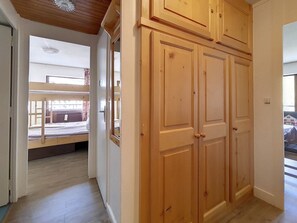 A room with a wooden wardrobe, a bed with a view, and a window. - Spacious apartment · Ski-in/Ski-out · Sunny balcony (Les Menuires)