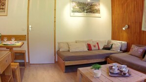 A cozy room with a wooden ceiling, a sofa, a small table with cups, and a framed picture on the wall.