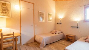 A cozy room with a wooden ceiling, a bed with a white bedspread, a small bedside table, and a chair.