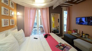 A hotel room with a bed, a TV, a balcony with pink curtains, and a mirror. - E4GG So sweet (París)