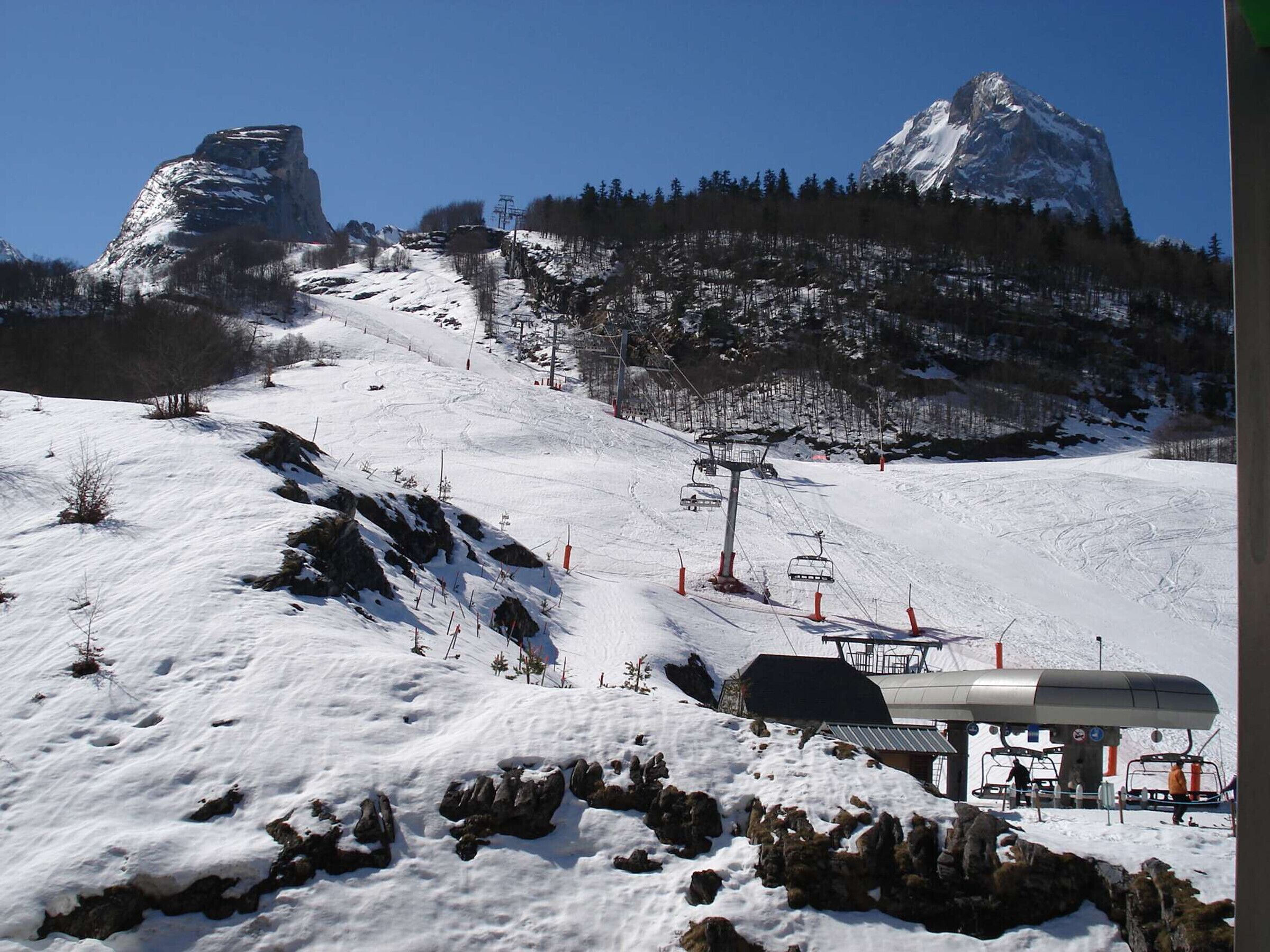 A ski resort with a chairlift, snow-covered slopes, and a mountain backdrop.