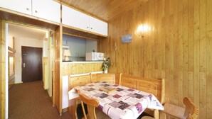 Une pièce chaleureuse, avec un décor en bois, comprenant une table à manger, des chaises et un coin cuisine équipé de placards et d’un four à micro-ondes.