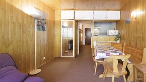 Une cabane en bois comprenant un coin repas, un canapé et une petite cuisine.