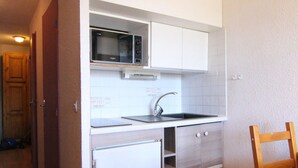 A compact kitchen with a microwave, sink, and built-in oven. - Cozy Studio for 4 in Alpe d'Huez, Close to Slopes & Shops, Balcony, Pets Welcome (Huez)