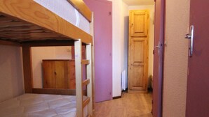 A narrow hallway with a bunk bed on the left and a wooden door at the end. - Cozy Studio for 4 in Alpe d'Huez, Close to Slopes & Shops, Balcony, Pets Welcome (Huez)
