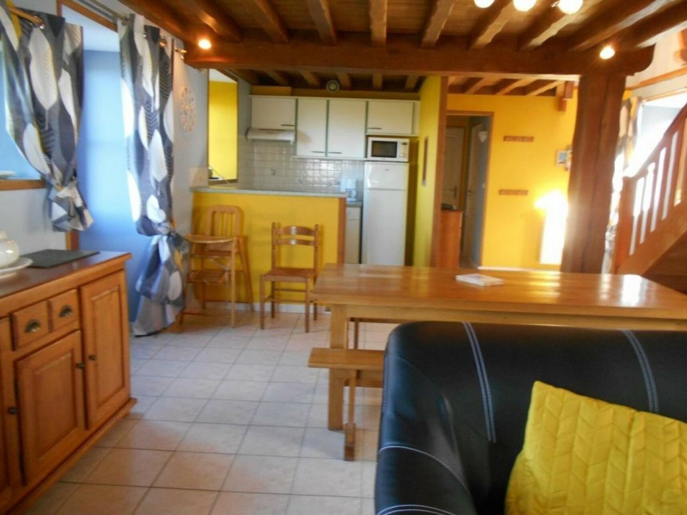 A compact living space with a sofa, a dining table, and a kitchen area with cabinets and a microwave.