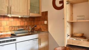 A kitchen with wooden cabinets, a Siemens dishwasher, a sink, and a large G letter on the wall. - Cozy 2-Room Apt for 4, 100m from Slopes, Balcony, Pet-Friendly, WiFi - Méribel (Méribel)