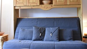 A bed with a blue headboard, two pillows, and a wooden cabinet above it. - Cozy 2-Room Apt for 4, 100m from Slopes, Balcony, Pet-Friendly, WiFi - Méribel (Méribel)