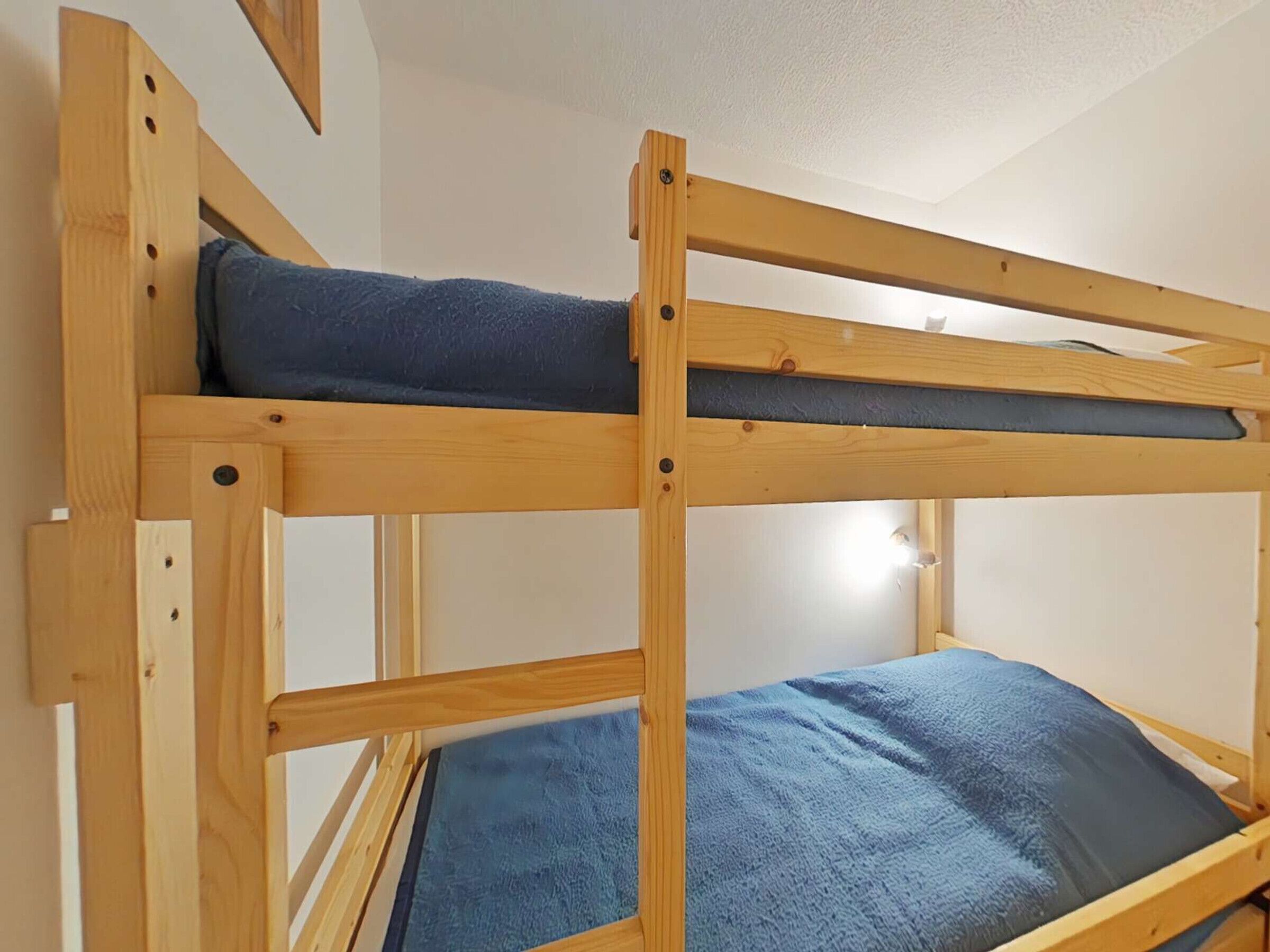 A bunk bed with a blue mattress and a wooden frame.