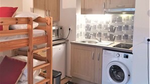 A compact kitchen with wooden cabinets, a microwave, a sink, and a washing machine.