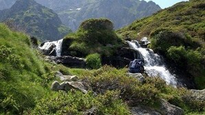 A mountainous landscape with a waterfall and lush greenery.