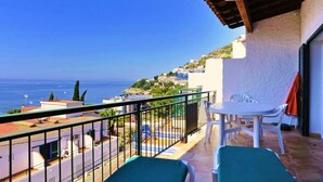 Un balcone con vista sul mare, un tavolo e due poltrone.