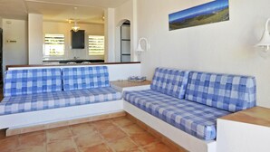 Un soggiorno con un divano a quadri blu e bianchi, una cucina sullo sfondo e un quadro appeso al muro.