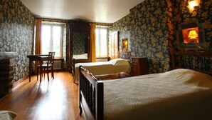 Een slaapkamer met een bed, een bureau en een stoel. Er is een raam met gordijnen en een lamp aan de muur.