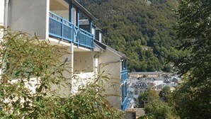 A building with a balcony, surrounded by greenery and mountains in the background. - Apartment Cauterets, 1 bedroom, 4 persons (Cauterets)